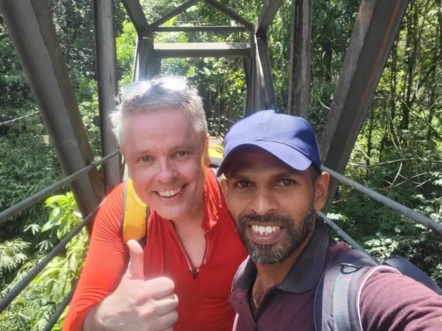 A local guide and visitor on a bridge surrounded by rainforest